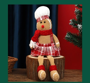 Detail of Christmas gingerbread man doll in red plaid skirt sitting on a wood stump