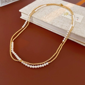 Detail of vintage double-layer necklace with faux pearls and golden metal chains on a book