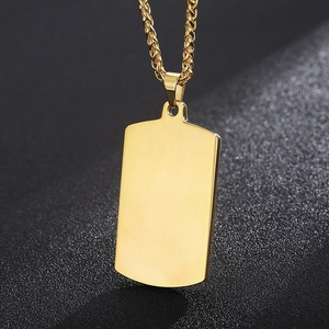 Close-up of polished gold rectangular pendant on a twisted chain against dark texture