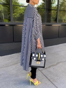 Detail of elegant black and white striped shirt dress with irregular hem and neon heels