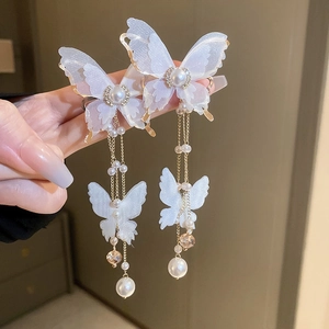 Detail of lace butterfly earrings with long gold tassels and faux pearls in macro view