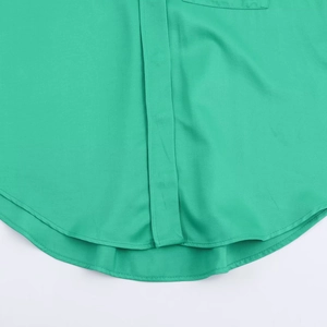 Detailed macro view showing smooth satin fabric texture and curved hem of the green shirt