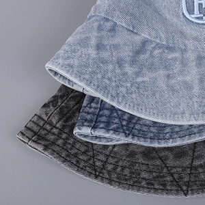 Détail de bobs en jean brodés en coloris bleu clair, bleu moyen et gris foncé délavé