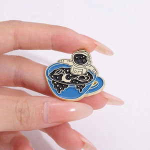 Cartoon astronaut in a blue teacup enamel brooch pin with golden metal edges
