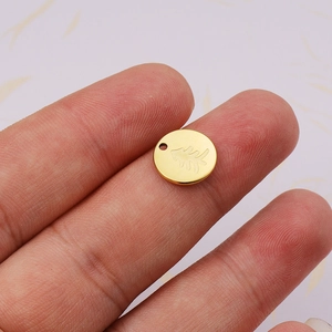 Polished 18K gold tree pendant made of stainless steel shown being held by fingers