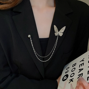 Detail of silver butterfly brooch with double layer chains on a black suit lapel