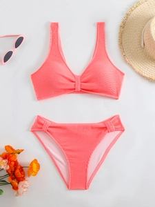 Flat lay of coral pink waffle textured bikini set with summer hat and sunglasses