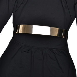Détail d'une ceinture métallique dorée polie sur une robe noire plissée pour femme