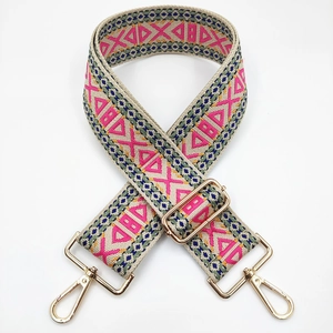 Close-up of geometric pink and green woven bag strap with golden metal swivel hooks