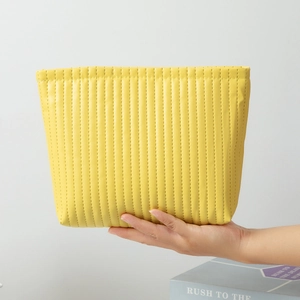 Detail of yellow quilted waterproof makeup bag showing PU leather texture and hand-held size