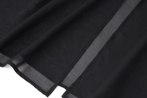 Macro view of sheer black tulle fabric showing delicate mesh texture and sewing details
