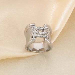 Close-up of silver wide band ring with crisscross pavé diamonds on champagne silk fabric