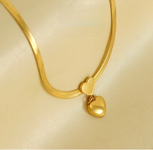 Macro detail of high-polish 18K gold heart pendant necklace on silk fabric
