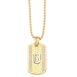 Macro detail of a gold military dog tag pendant with sparkling pavé letter U and bead chain