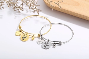 Detail of adjustable heart bracelets in gold and silver with Love charms on a tray