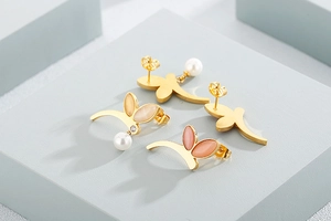 Detail of gold floral earrings with pink opal and white pearl drops on elegant props
