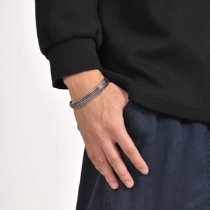 Detail of vintage silver braided steel cuff bracelet on model wearing black hoodie