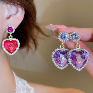 Détail des boucles d'oreilles cœur en cristal avec pierres précieuses fuchsia et violettes