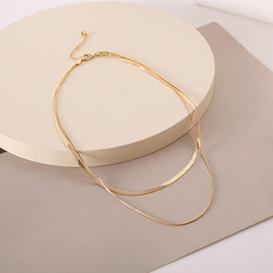 Golden layered herringbone snake chain necklace with adjustable lobster clasp on beige stand