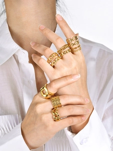 Close-up of stacking gold chain rings with Cuban and Figaro designs on fingers