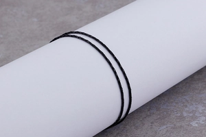 Detail of minimalist black thin chain necklace wrapped around a white cylinder