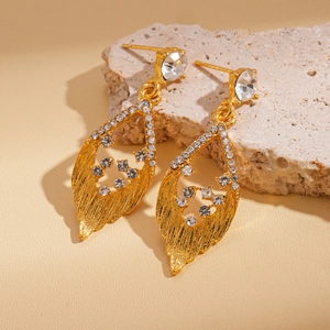 Detail of gold leaf drop earrings with sparkling crystals on natural stone background