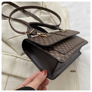 Detail view of brown vintage floral pattern handbag with leather strap and golden hardware