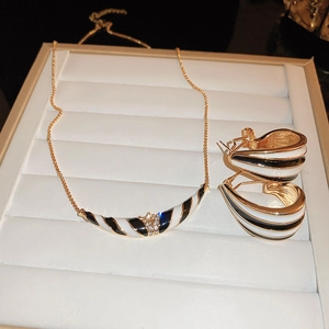 Detail eines Gold-Schmucksets mit schwarz-weißen Streifen und funkelnden Kristallen