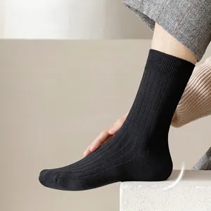 Men's black cotton crew socks with vertical stripes and reinforced heel on stone surface