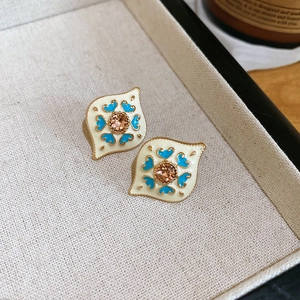 Detail of diamond-set rhombus leaf earrings with beige enamel and blue heart pattern