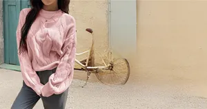 Detail of pink cable-knit sweater texture and classic round neck on a casual holiday dress
