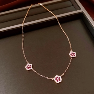 Detail of 18K gold plated flower pendant necklace with red petals and diamond accents