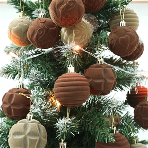 Brown and beige flocked velvet Christmas balls with embossed patterns on a lit tree