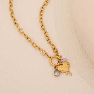 Detailed close-up of a gold heart pendant and drop crystals on a stainless steel chain