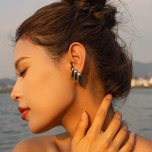 Close-up of irregular silver wavy earrings with modern metallic texture on model