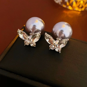 Détail macro de boucles d'oreilles papillon plaquées or avec perle grise et zircon clair