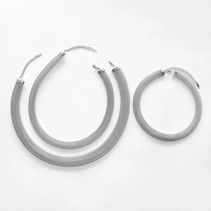 Three pieces of silver mesh chain necklaces in various lengths on a grey background