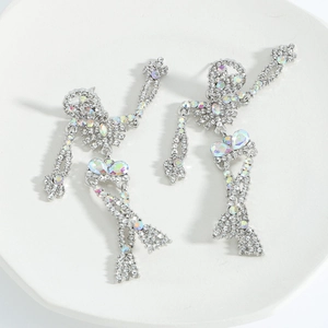 Detailed macro of silver skull mermaid earrings with colorful rhinestones on a tray