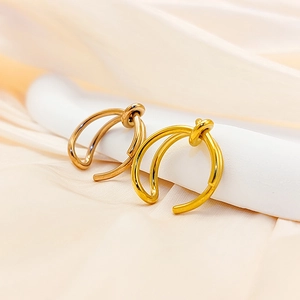 Macro shot of minimalist knotted gold and rose gold ear cuffs on soft satin fabric