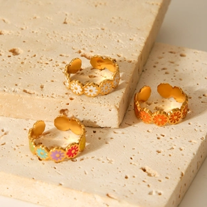 Adjustable stainless steel daisy rings with colorful enamel on beige stone display