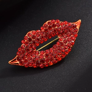 Close-up of red rhinestone lips brooch with gold base on a textured black background