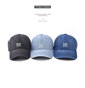 Detailed embroidery of NYC letters on washed denim baseball caps in multiple colors