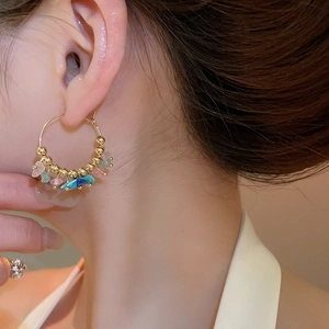 Detail of bohemian gold hoop earrings with multi-colored irregular stone charms on model