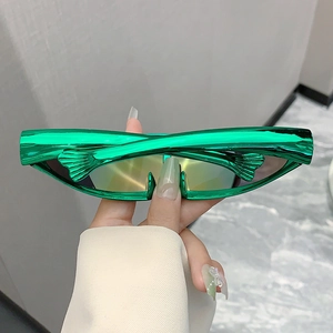 Detail of metallic green Y2K futuristic sunglasses featuring a unique fish-fin side design
