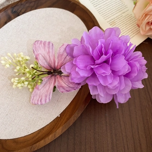 Vue détaillée d'une pince à cheveux fleur en tissu violet et papillon sur bois