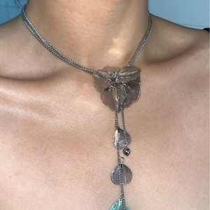 Vintage floral fringe necklace with large metallic flower pendant on model neckline