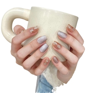 Handmade cat eye press-on nails with silver glitter and 3D floral accents on a ceramic cup