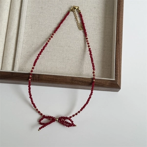 Detail of red faceted crystal bead necklace featuring a handmade woven bow pendant