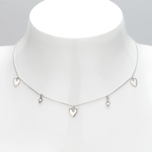 Close-up of silver necklace with heart and diamond-set rhombus charms on a white mannequin