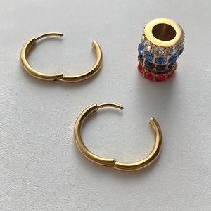 Detailansicht goldener Creolen aus Edelstahl mit einem funkelnden, bunten Strassstein-Anhänger
